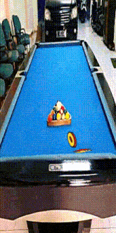 a pool table with balls on it and a car parked behind it