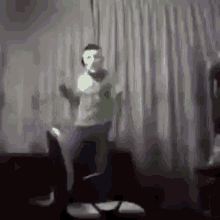 a man wearing a mask is dancing in a living room while sitting on a chair .