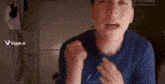 a young boy in a blue shirt is making a funny face with his mouth open .