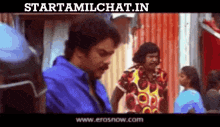 a man in a blue shirt is talking to another man in a colorful shirt in a scene from a movie .