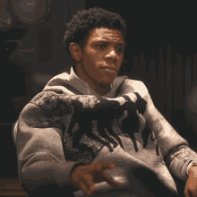 a man wearing a sweater with horses on it is making a stop sign