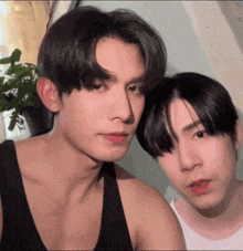 two young men are posing for a picture and one is wearing a tank top