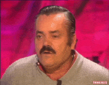 a man with a mustache is wearing a grey sweater and has a pink background behind him that says think jules