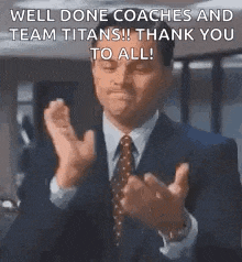 a man in a suit and tie is clapping his hands in a room .