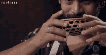 a man with a ring on his finger holds a bowl in front of a sign that says top chef