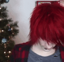 a girl with red hair is sitting in front of a christmas tree .