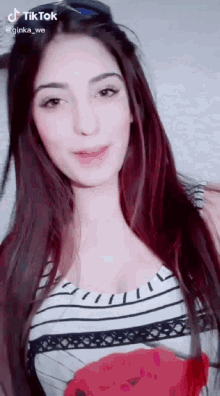 a woman with long red hair is wearing a striped top and a red flower on her shirt .