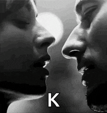 a black and white photo of a man and a woman kissing each other .