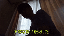 a silhouette of a man in front of a window with japanese writing on the bottom