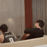 a couple of men are sitting on a couch in a living room .