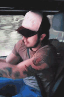 a man in a trucker hat is driving a vehicle