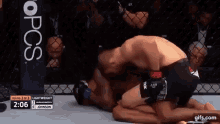 two men are wrestling in a cage and one of them is kneeling on the ground .