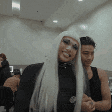 a woman in a white wig is smiling next to a man