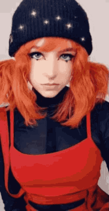 a girl with red hair is wearing a black beanie and a red top