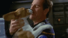 a man is holding a small puppy in his arms and the puppy is sniffing the man 's face .