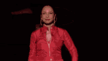 a woman in a red shirt and earrings is dancing on a stage .