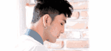 a close up of a man wearing earrings and a blue shirt .
