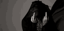 a black and white photo of a person covering their face with their hands and giving the middle finger