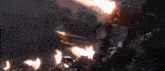 a group of people are standing in front of a machine gun that is shooting flames .