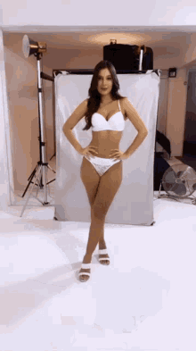 a woman in white lingerie is standing in front of a white backdrop