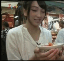 a woman in a white shirt is holding a plate of food
