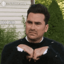 a man in a black sweater is making a funny face while holding his hands together .