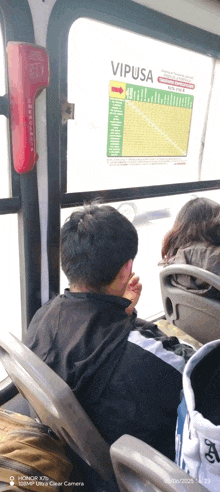 a person sitting on a bus with a vipusa sign on the window