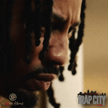 a close up of a man 's face with dreadlocks and the words trap city on the bottom