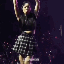 a woman in a plaid skirt is standing on a stage with a microphone and giving the middle finger .