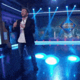 a man stands on stage in front of a sign that says hormiguero