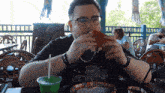 a man eating a sandwich and drinking a green drink
