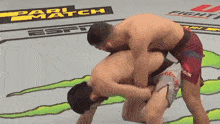 two men are wrestling in a ring with the word match on the floor