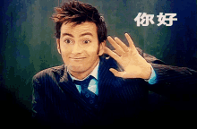 a man in a suit and tie is waving his hand in front of a green background with chinese writing