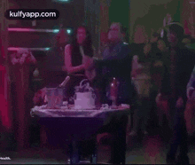 a man is standing in front of a table with a cake on it and a bottle of champagne .