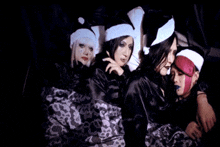 a group of women wearing santa hats and sleep masks are laying on a bed .