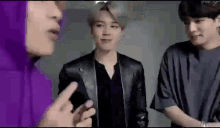 a group of young men are standing next to each other talking to each other .