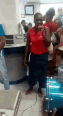 a woman in a red shirt is standing in front of a drum in a store .