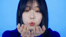 a woman is blowing a kiss with her hands .