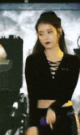 a woman in a black crop top is standing on a stage holding a purple object .