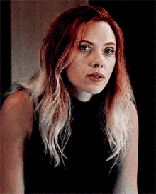 a close up of a woman with long red hair wearing a black shirt .