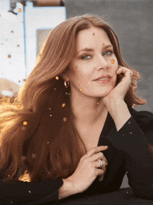 a woman with long red hair is wearing a black dress