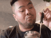 a man with a beard is eating something from a ladle