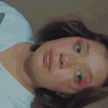 a close up of a woman 's face with colorful makeup on her eyes .