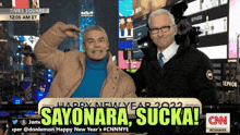 two men are posing for a picture in front of a sign that says sayonara sucka