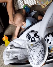 a baby is laying in a bouncer next to a spoon that says ' s ' on it