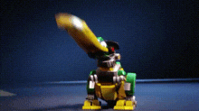 a green and yellow lego dinosaur is sitting on a table .