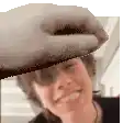 a close up of a person wearing sunglasses and a hat with a hand on it .