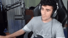 a man wearing headphones is sitting in front of a microphone in a chair .