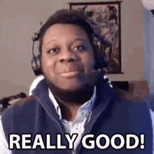 a man wearing headphones and a vest is making a funny face and saying `` really good '' .