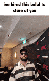 a man wearing sunglasses and a striped shirt stands in front of a ufc banner
